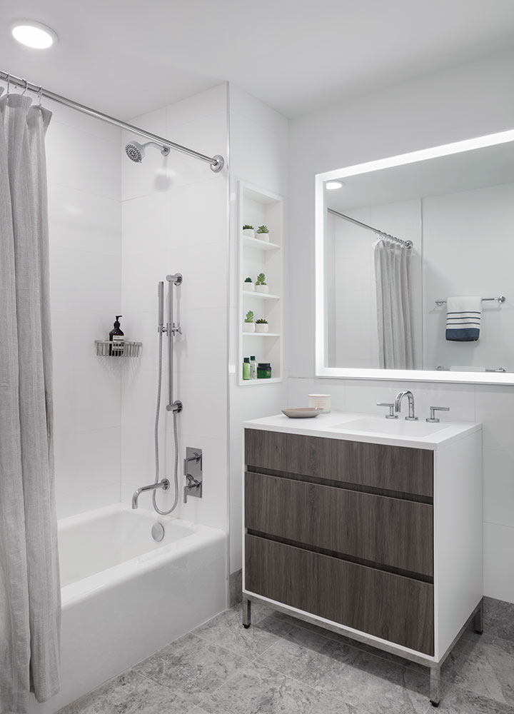 The Brooklyn Crossing bathrooms include marble floors and porcelain walls with illuminated vanity mirrors.